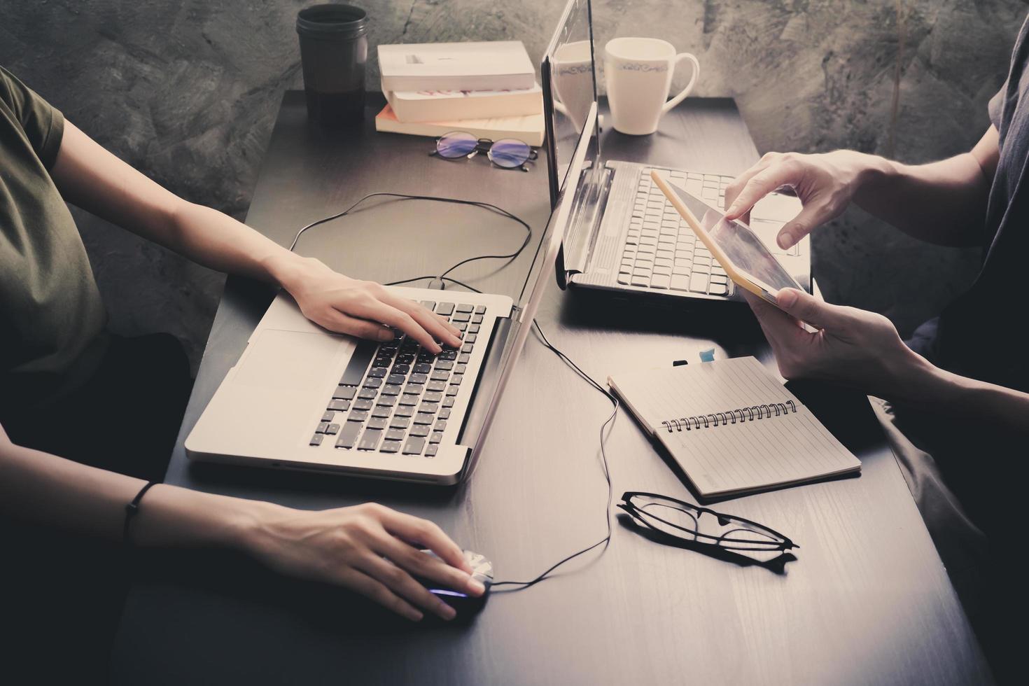 Coworkers working on the same desk, they are using a laptop with tablet, Start up business concept, Vintage tone photo