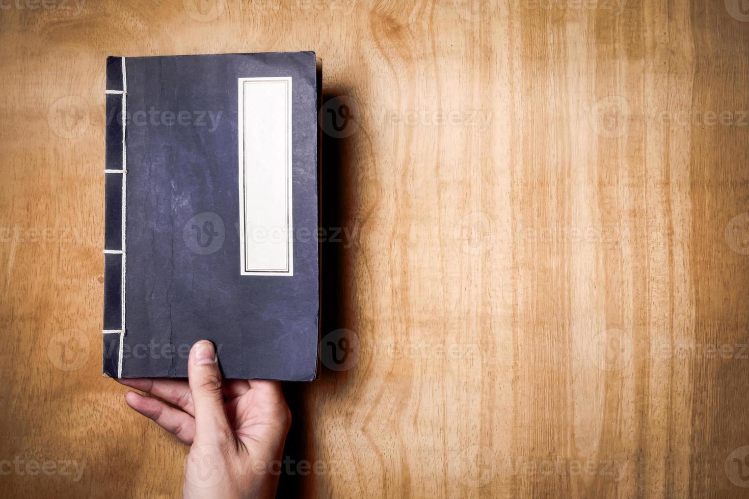 Top view of hands holding a book on wood background. Free space for text photo