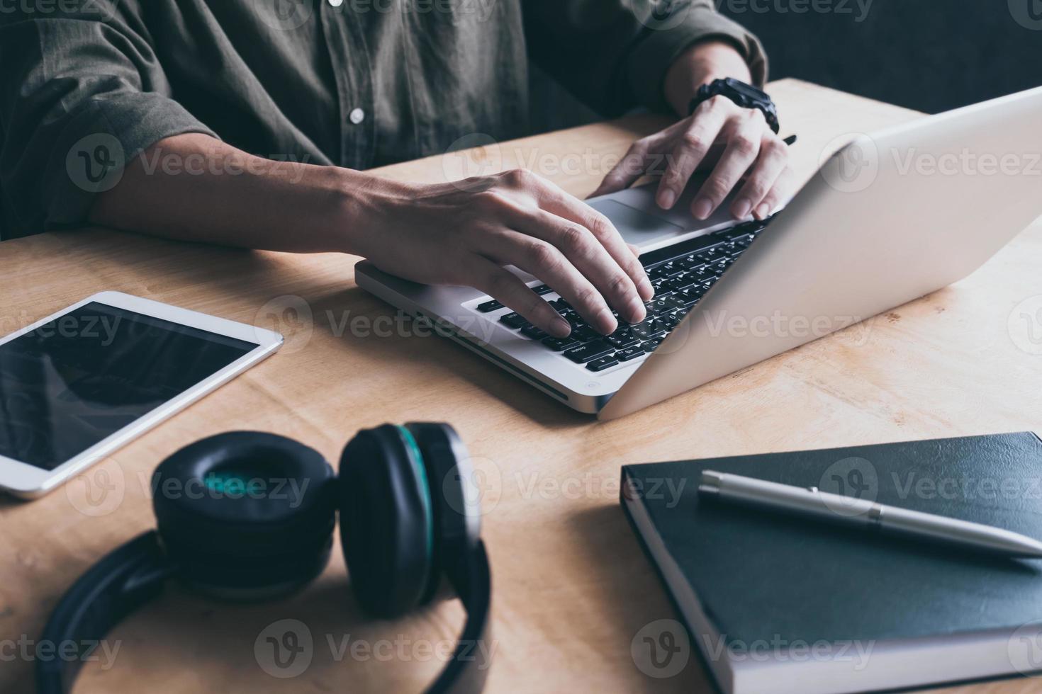 primer plano de un hombre casual que usa una computadora portátil en el escritorio en casa. foto