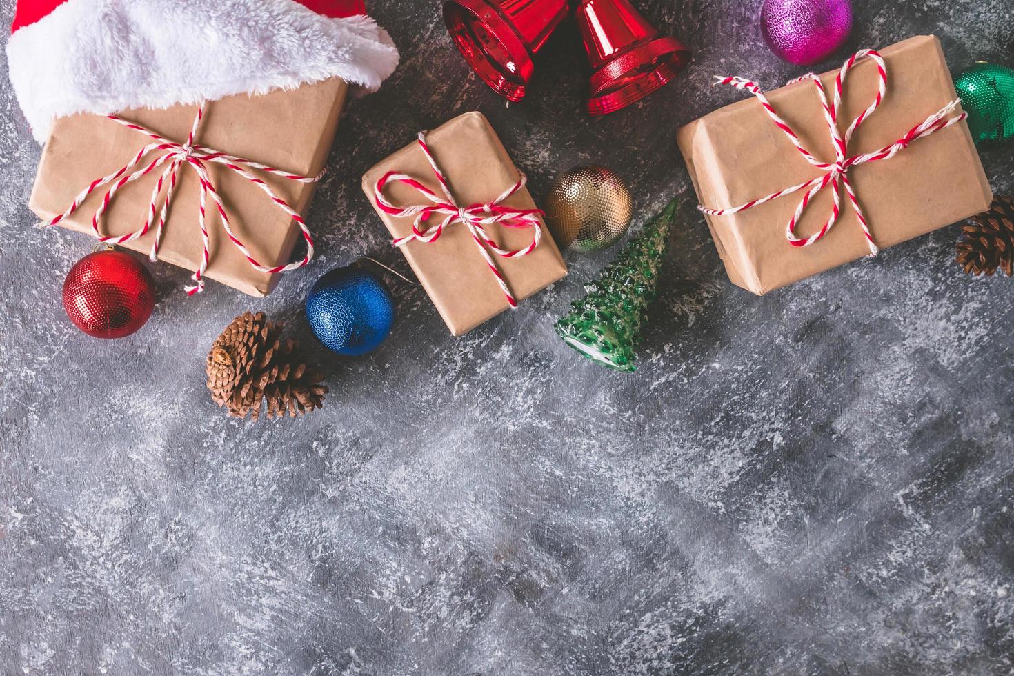 Top view of gift packages wrapped in brown paper with christmas decoration on gray grunge background. Free space for text photo