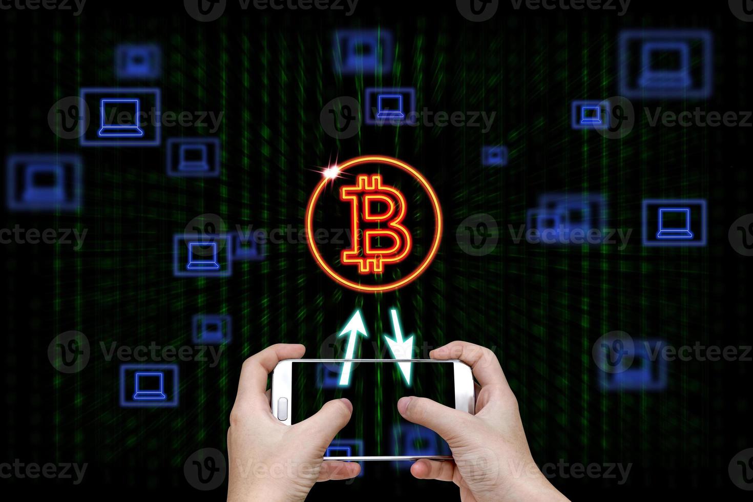 Human hand holding mobile smart phone with bitcoin symbol and laptop icons on binary background photo