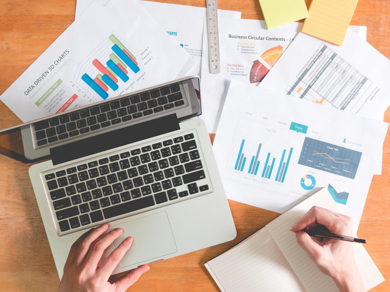 Top view of Businessman using laptop with analyzing investment charts on the office desk. photo