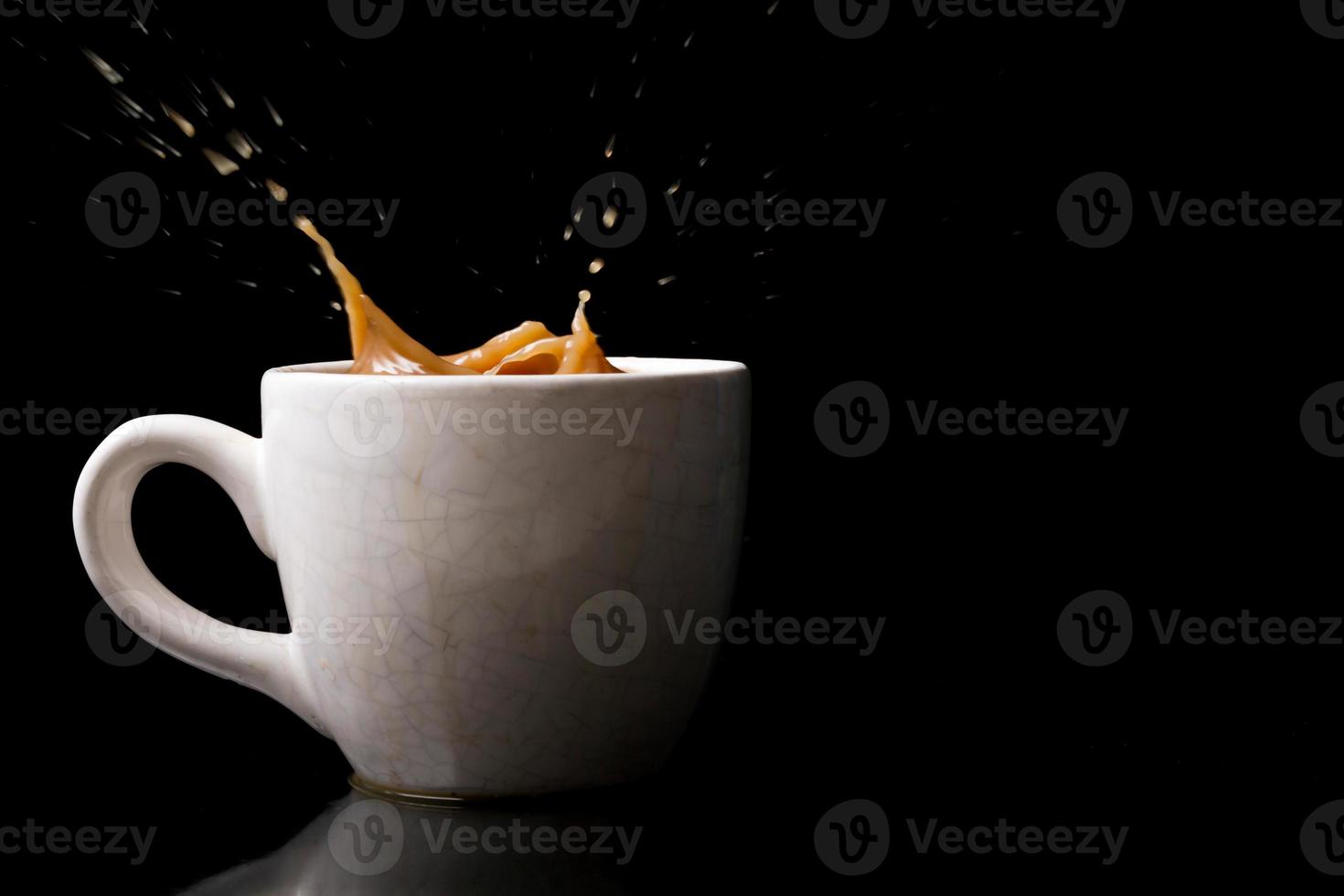 Cup of splashing coffee on black background photo