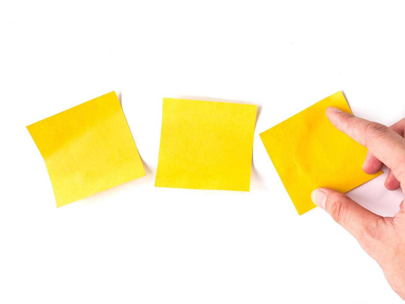 Yellow stick notes paper with hand on white background photo