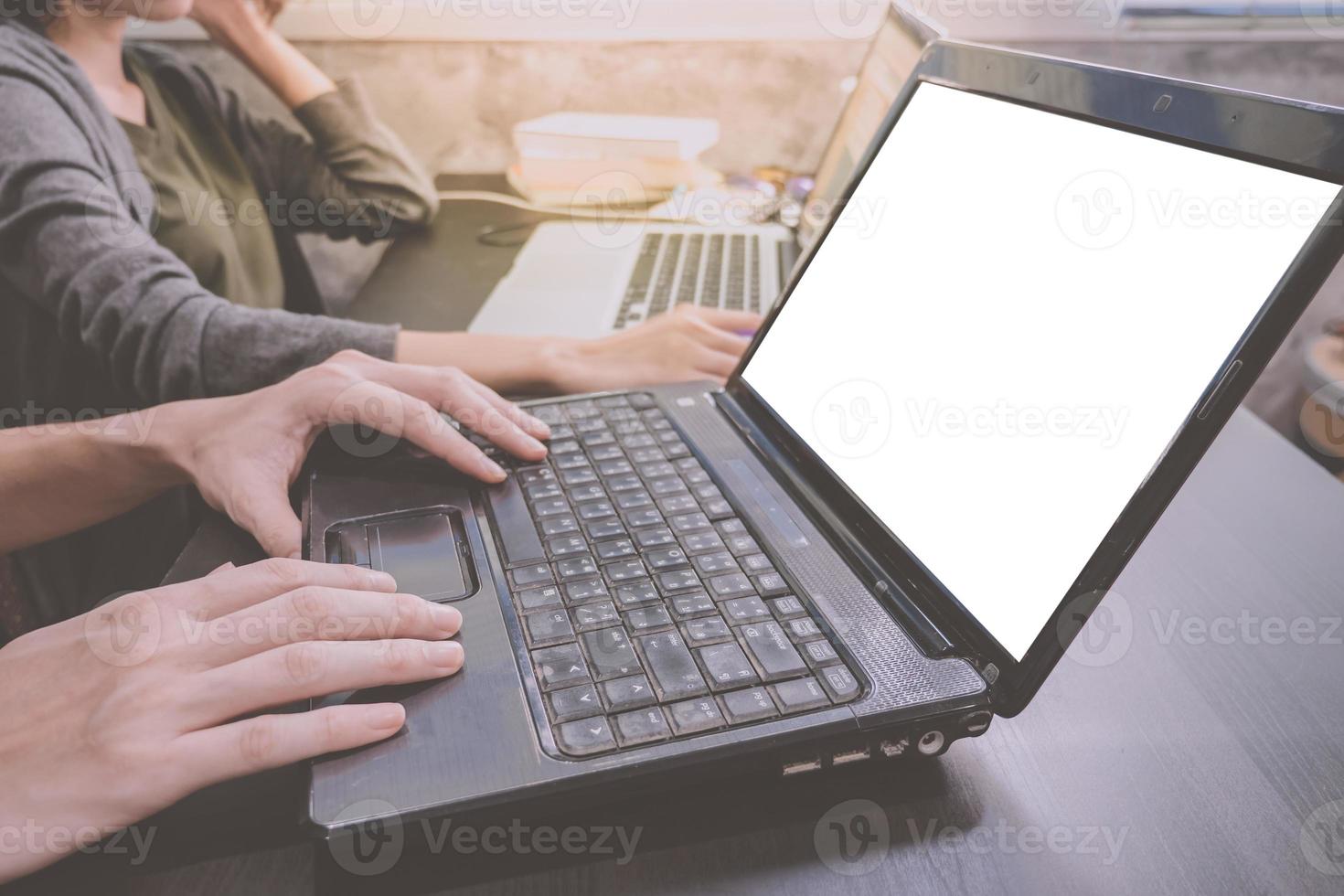 Business partners working together on the same desk, they are using a laptop with blank screen, Start up business concept photo