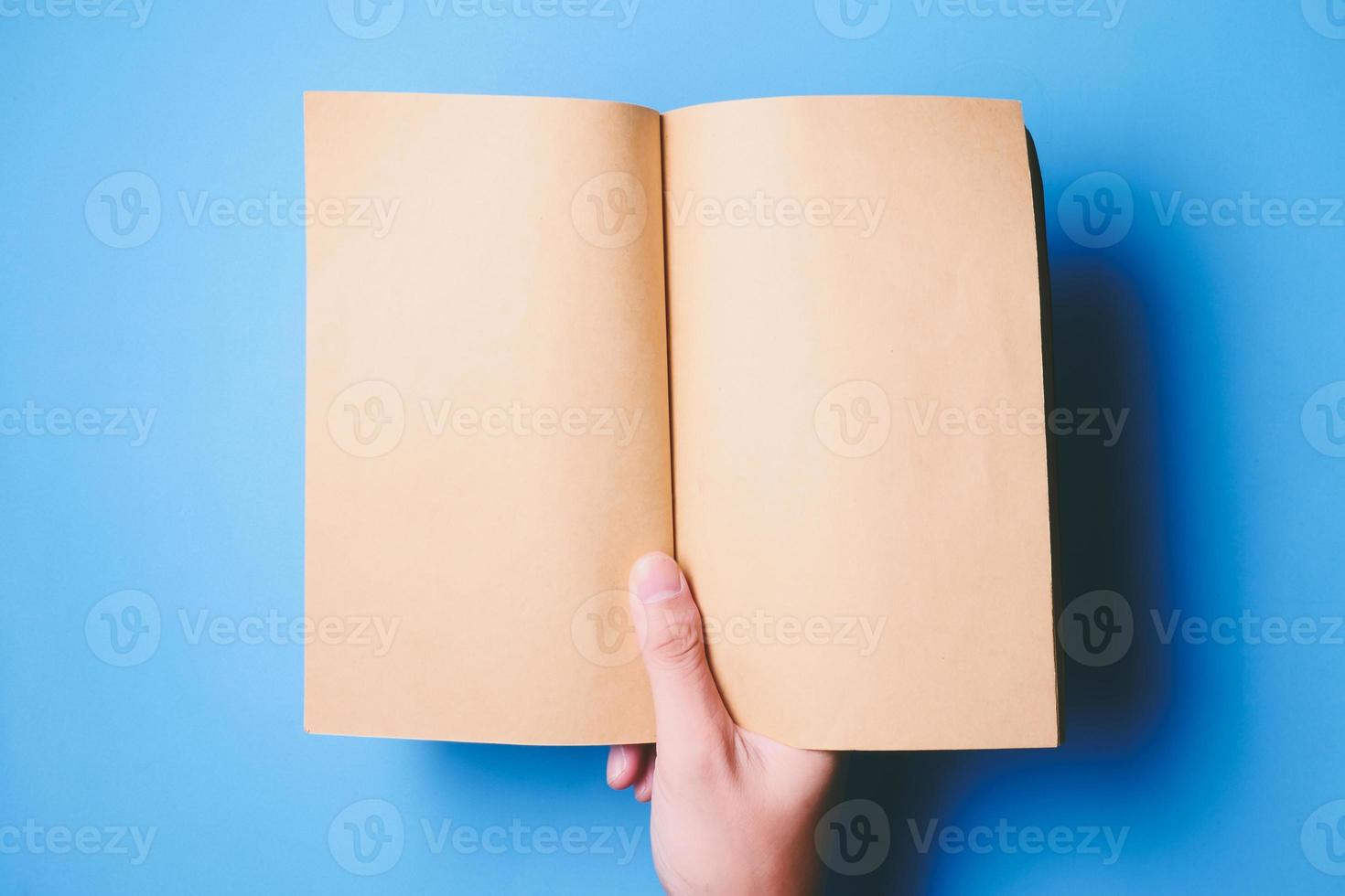 Top view of hands holding a blank book ready with copy space ready for text on blue background. photo