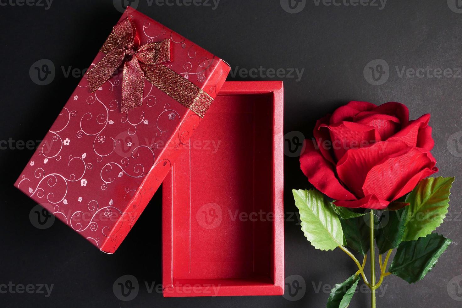 Empty red gift box with red rose on black background. Concept of Valentine Day. photo