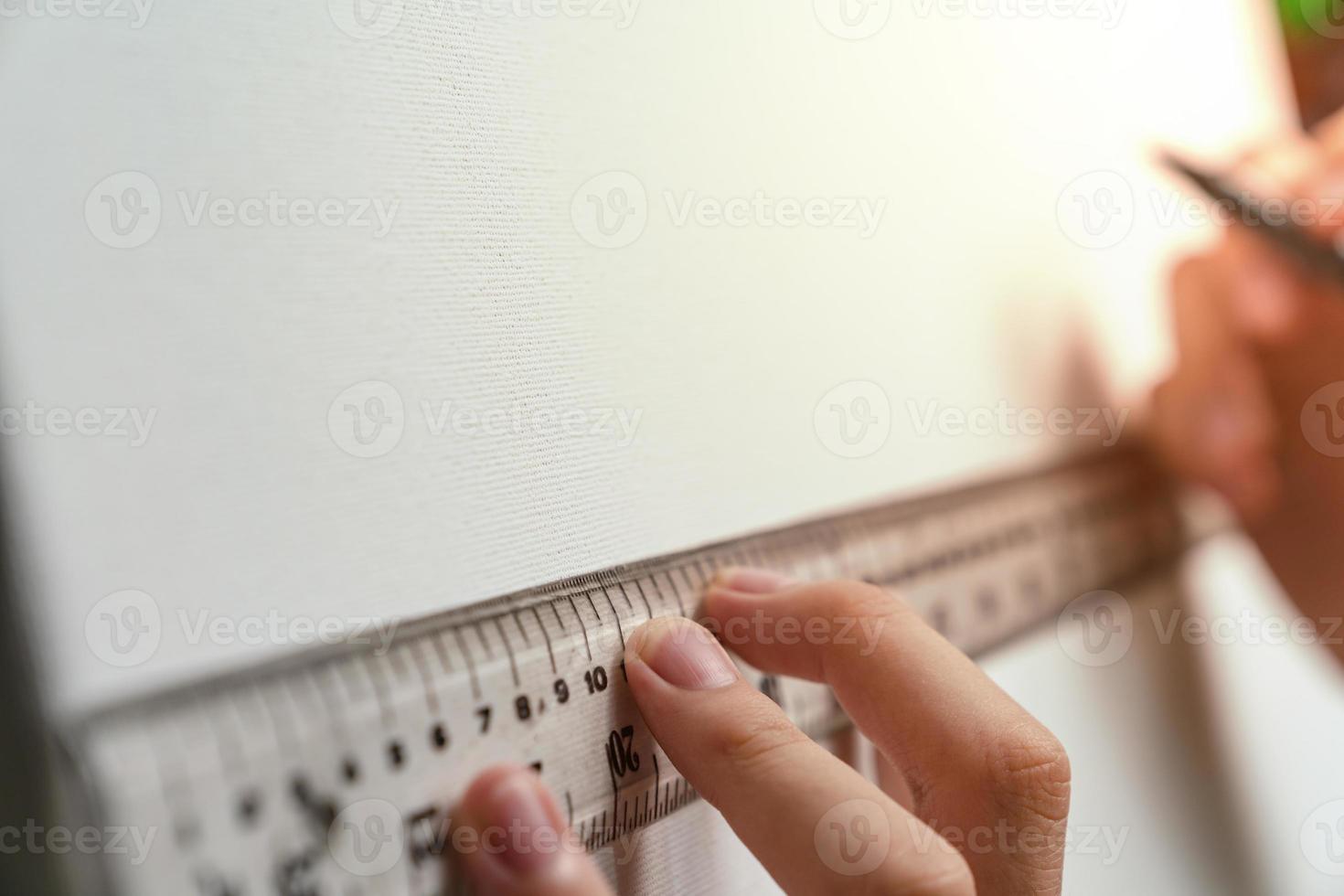 hand holding ruler and clutch-type pencil with canvas background photo