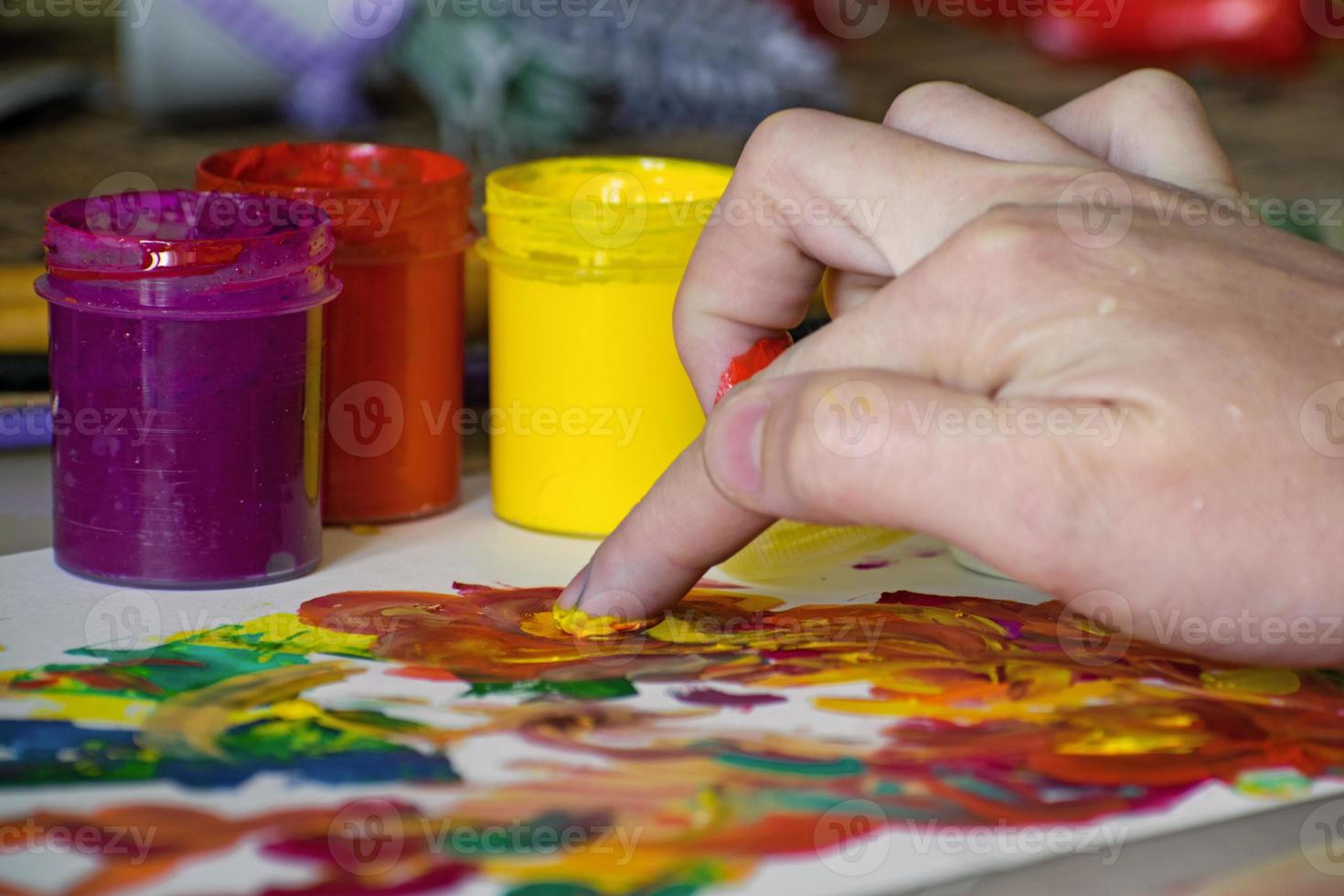 Hand of a girl mixing colors with fingers for painting. Abstract painting with gouache. Finger paint photo