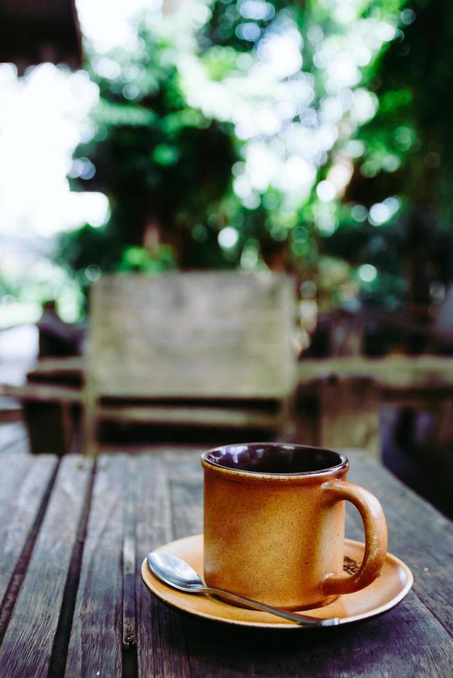 taza de café en la mesa de madera en la cafetería. filtro de grano de películas. foto