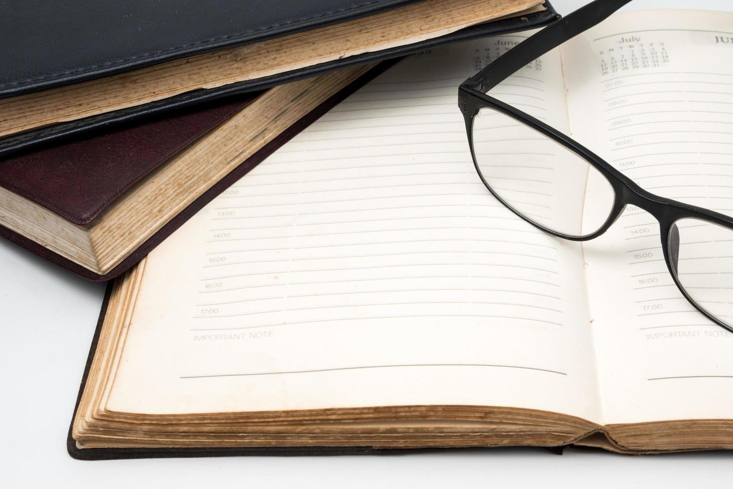 A stack of old books with notebook and eyeglasses on a white background. photo