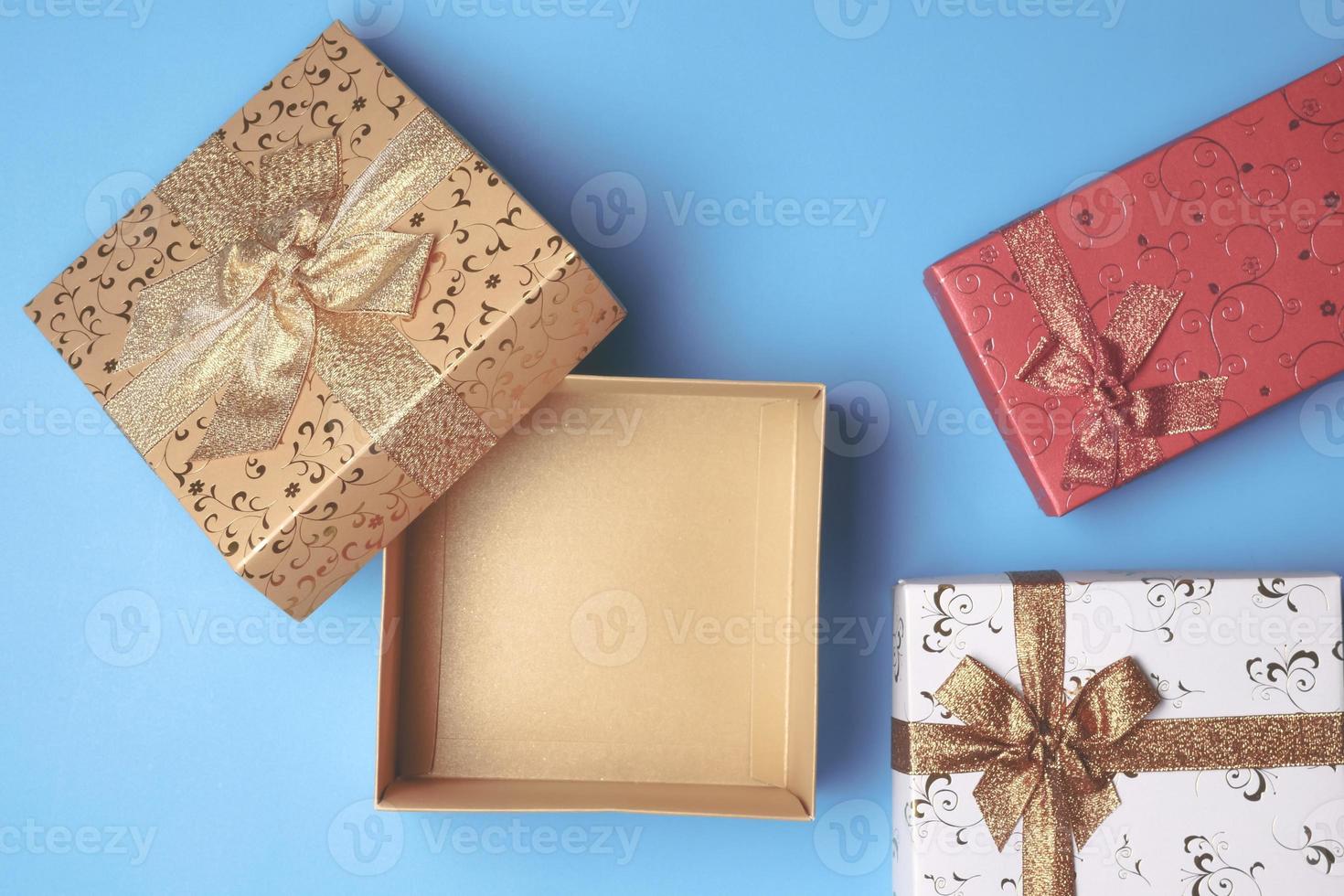 Top view of open gift box and presents on blue background. photo