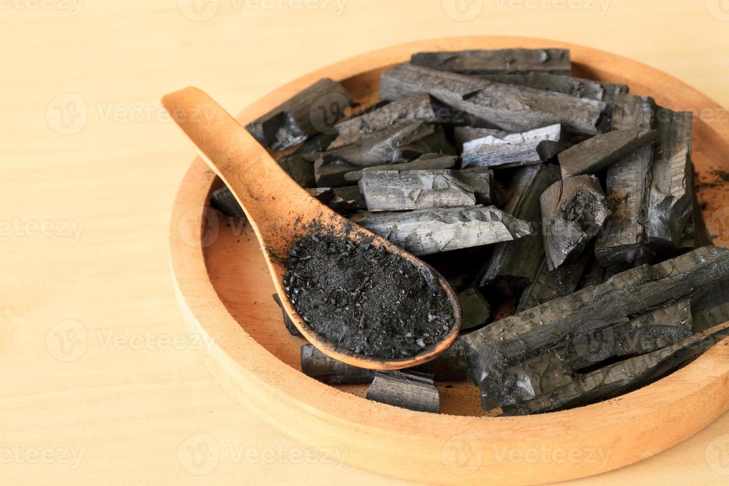 Charcoal and charcoal powder on wooden table background. photo
