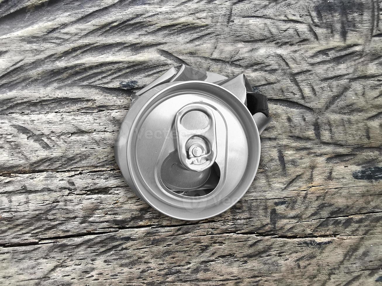 Soda crushed junk can on vintage wood texture background, top view photo