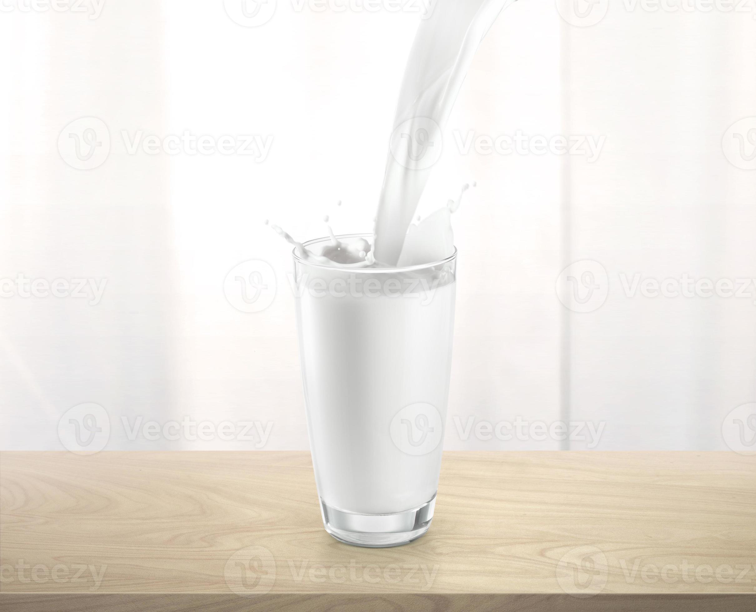 Pouring milk into glass cup with splashing, on wooden table 10724504 ...