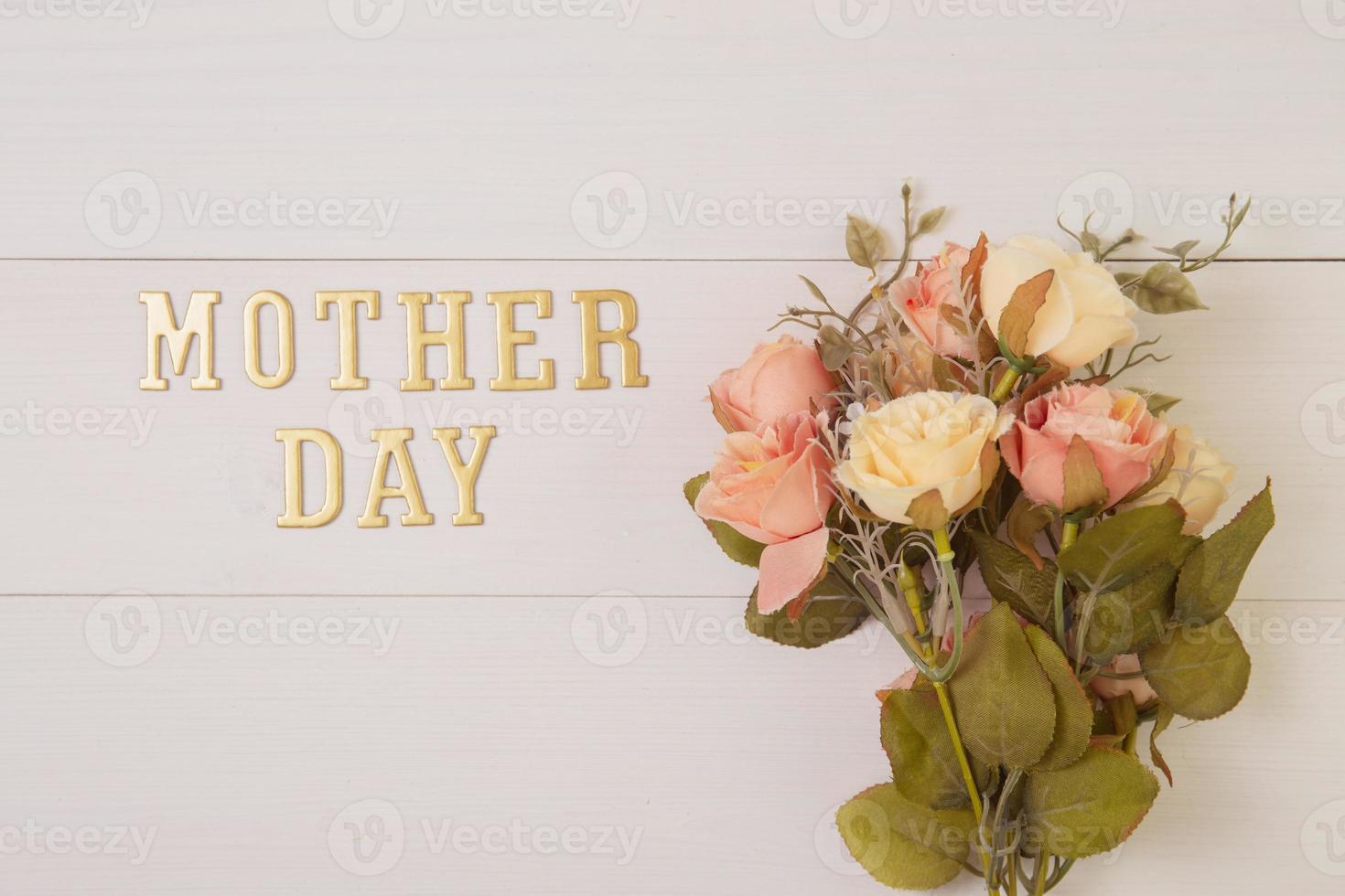 Beautiful flower and text mother day on wooden background with romantic pastel tone, spring or summer nature for decoration, bouquet floral and word or message for gift on desk, holiday concept. photo