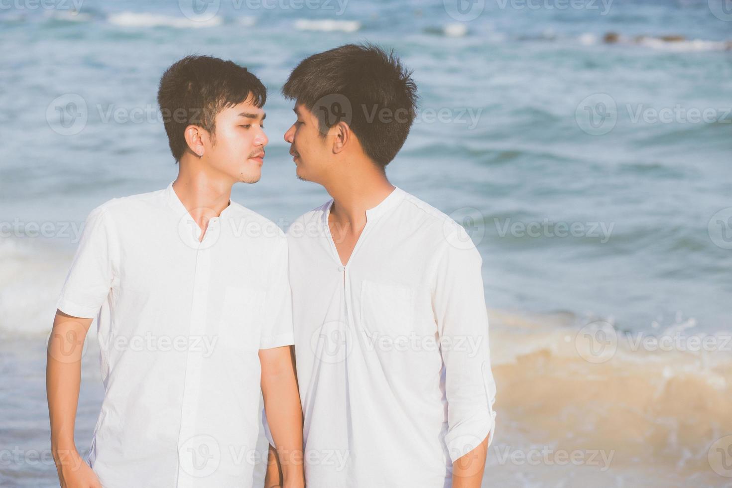 Homosexual portrait young asian couple standing together on beach in summer, asia gay holding hands going sea for leisure and relax with romantic and happy in vacation at sea, LGBT with legal concept. photo