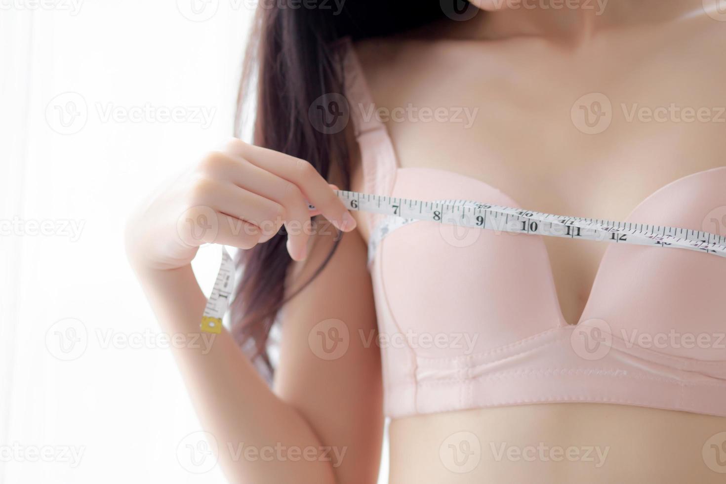Closeup beautiful young asian woman sexy body slim measuring breast for control weight loss in the room, beauty asia girl figure thin measure size of bust for diet, health and wellness concept. photo