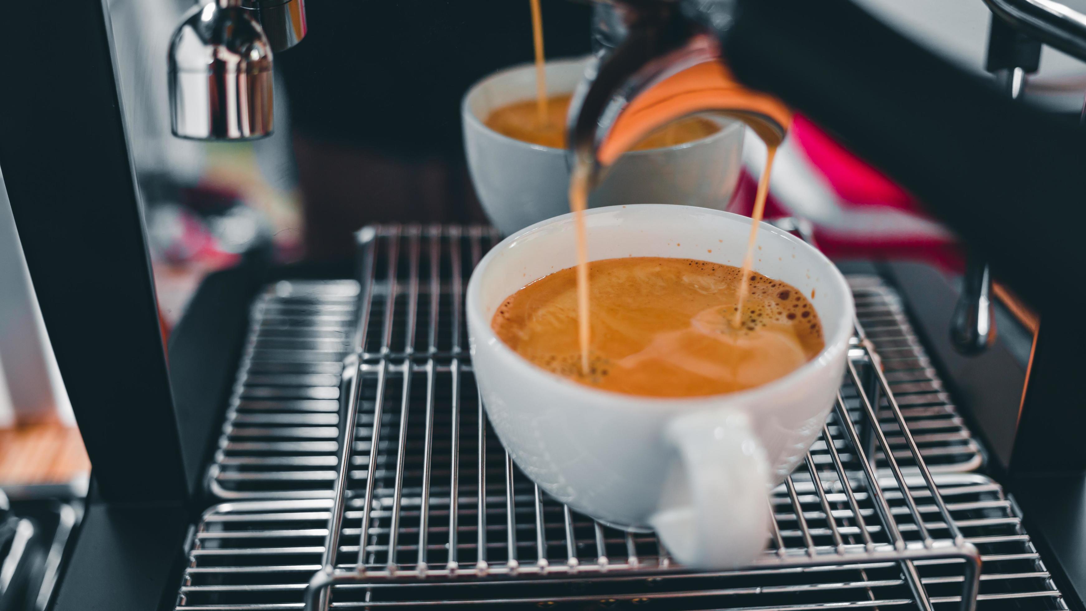Closeup of espresso pouring from coffee machine flowing into the coffee cup make coffee for