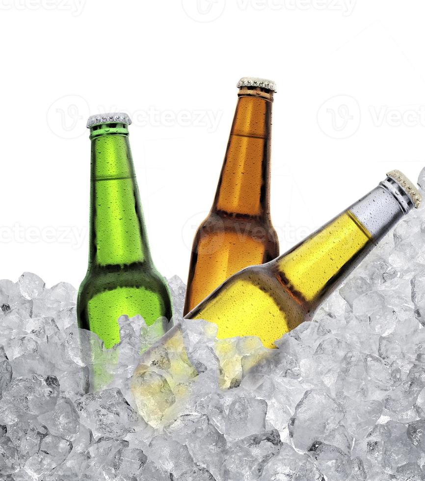 tres botellas de cerveza en cubitos de hielo. aislado sobre fondo blanco foto