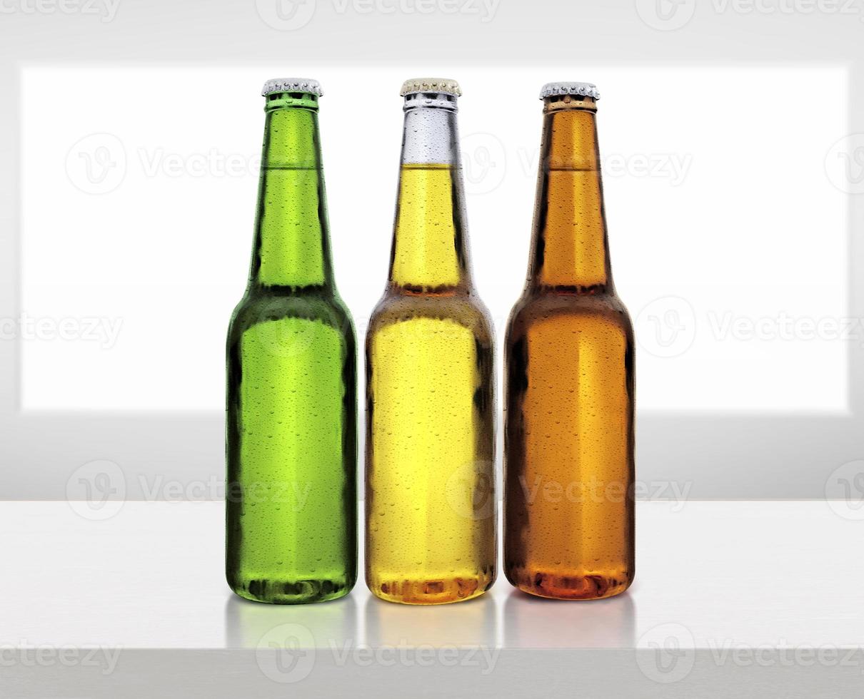 Beer bottle with water drops on white wooden table photo