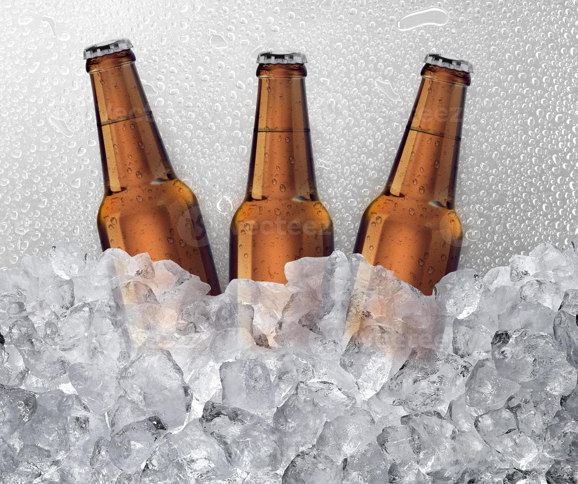 tres botellas de cerveza enfriándose en cubitos de hielo. fondo de gota de agua foto