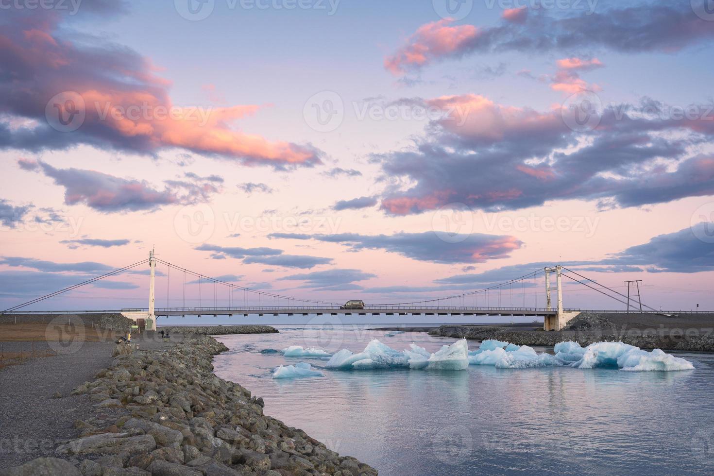 Beautiful sunset over suspension bridge on Jokulsarlon glacial river lagoon with iceberg floating in southern of Vatnajokull National Park at Iceland photo