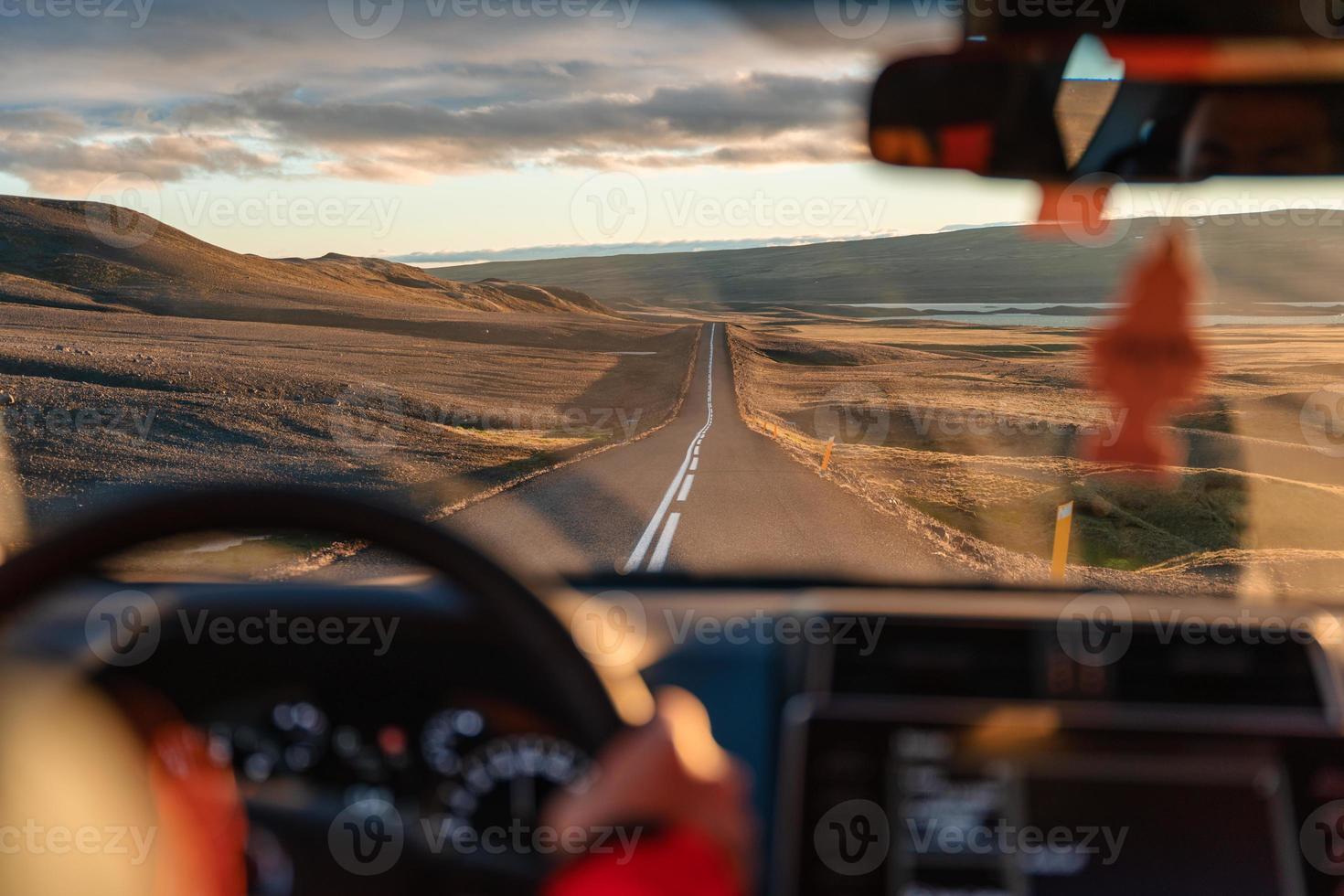 Man driving a car through wilderness on asphalt road in the sunset photo