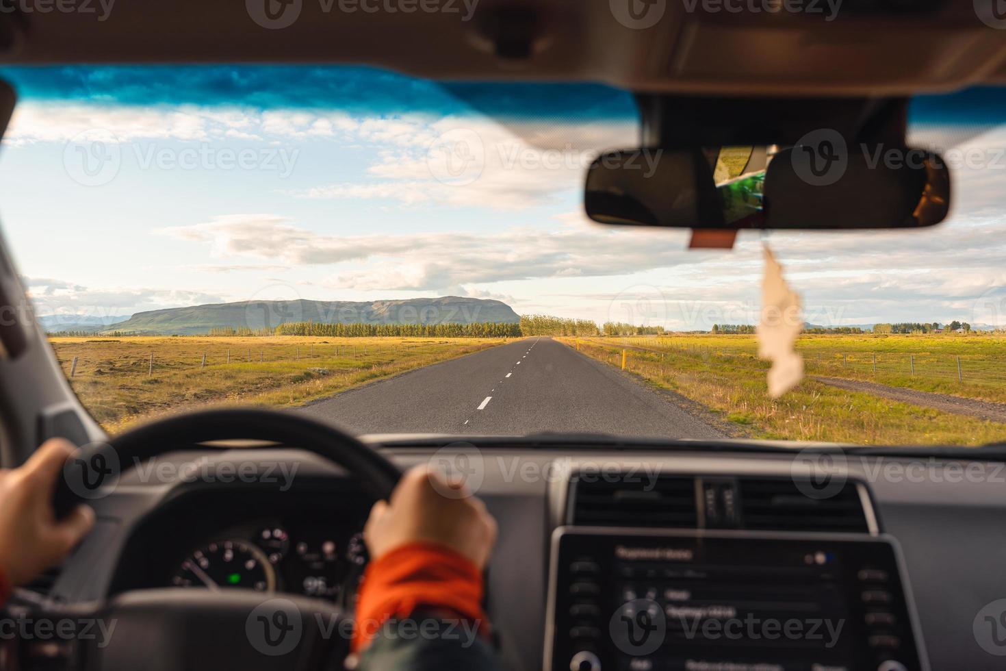 Road trip with man driving a car on highway through the field in the evening photo