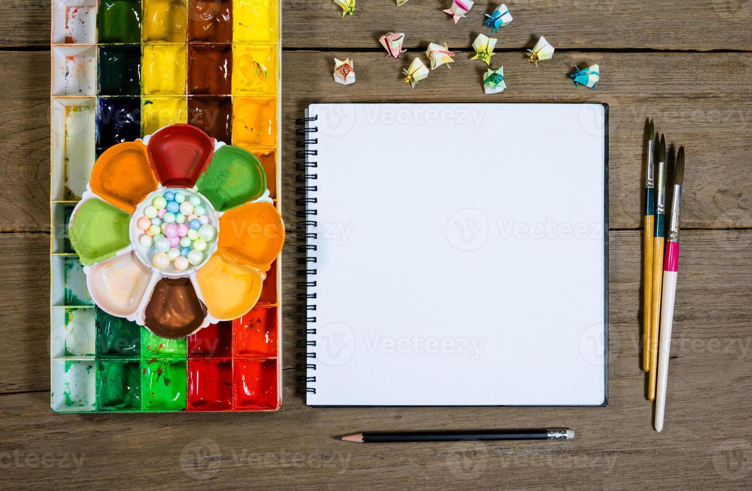 closeup open note book with tray colors on wood background photo
