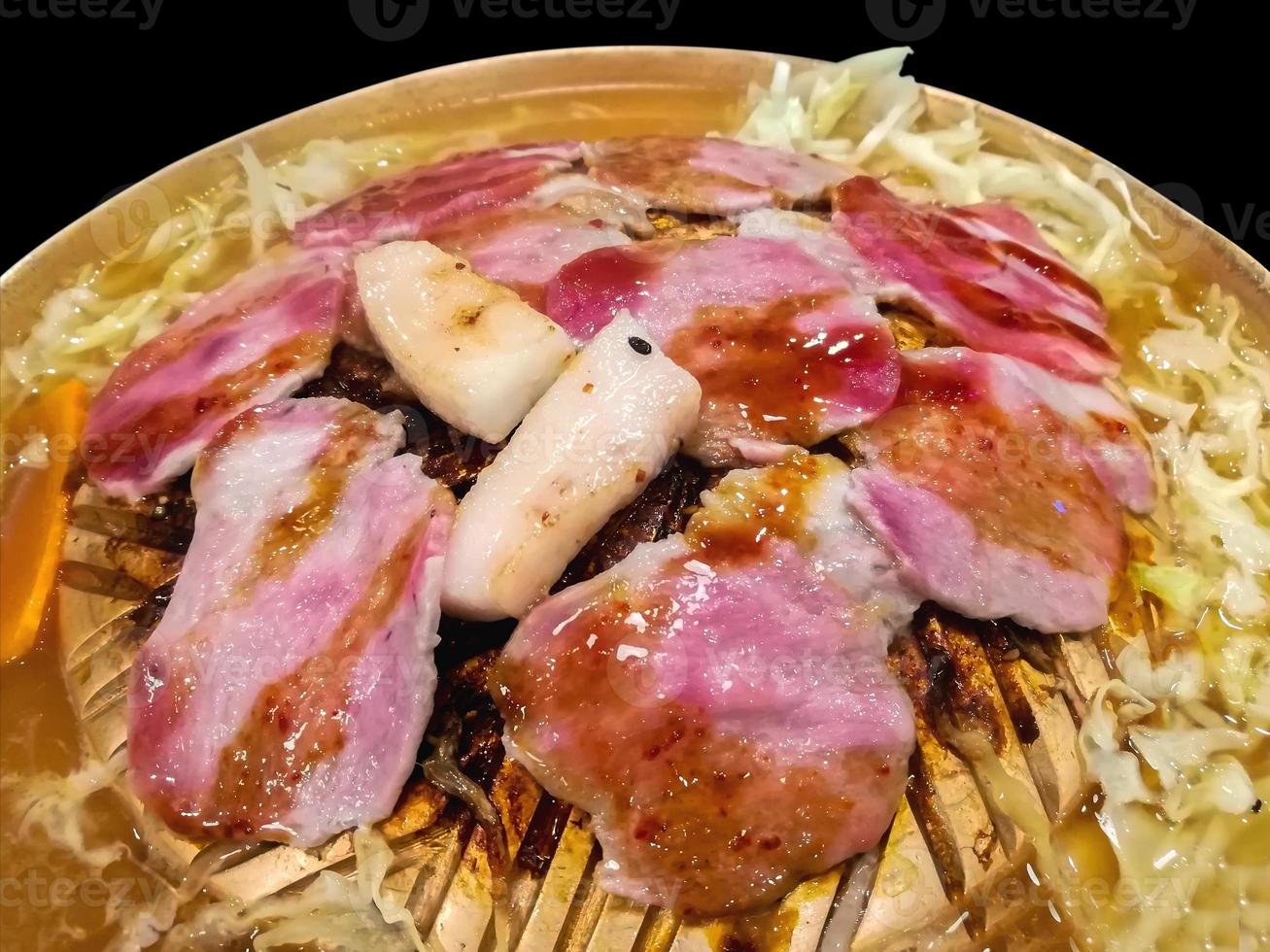 Korean food, Pork sliced grilling on brass hot pan with Vegetable soup isolate on black background photo