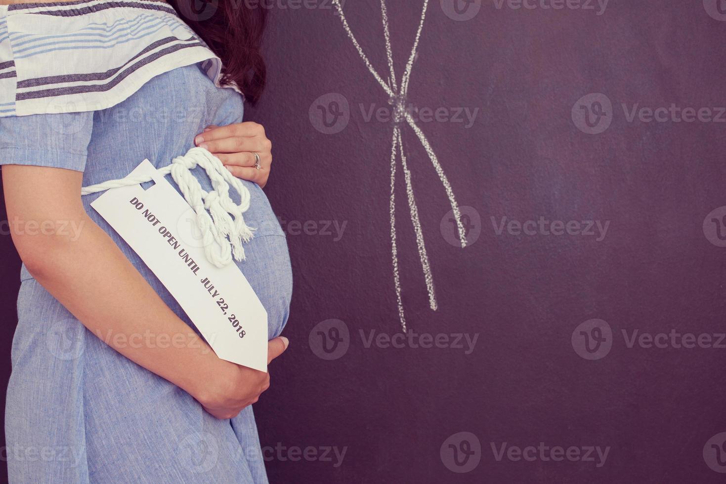 Portrait of pregnant woman in front of black chalkboard photo