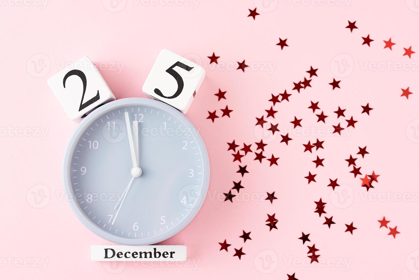 Christmas background with alarm clock and stars confetti on pink background photo