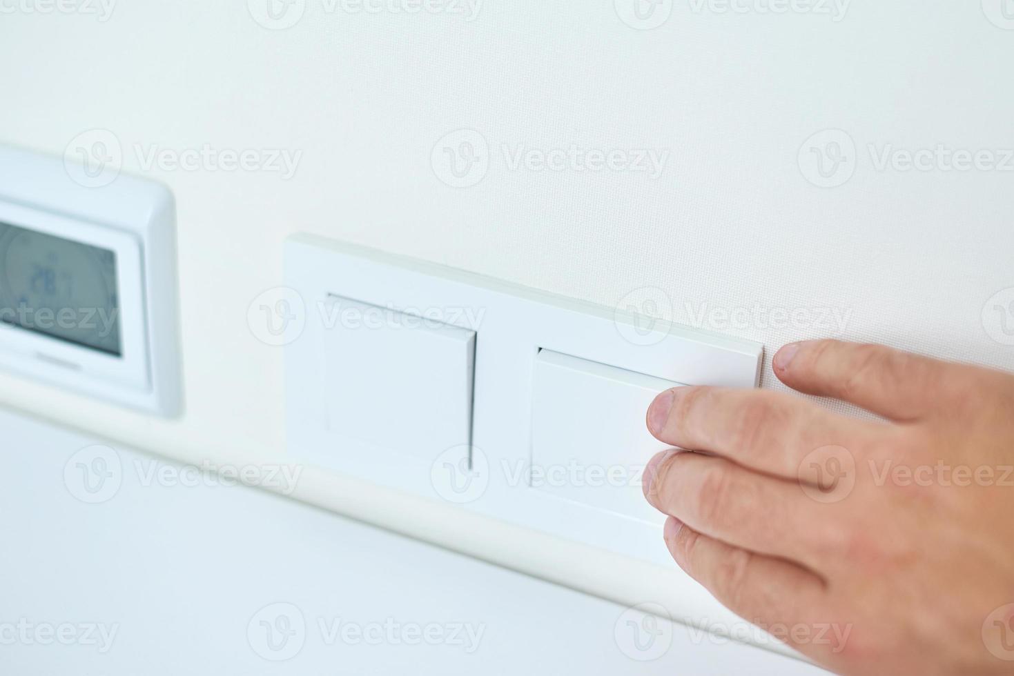 Hand is turning on or off on light switch, closeup photo