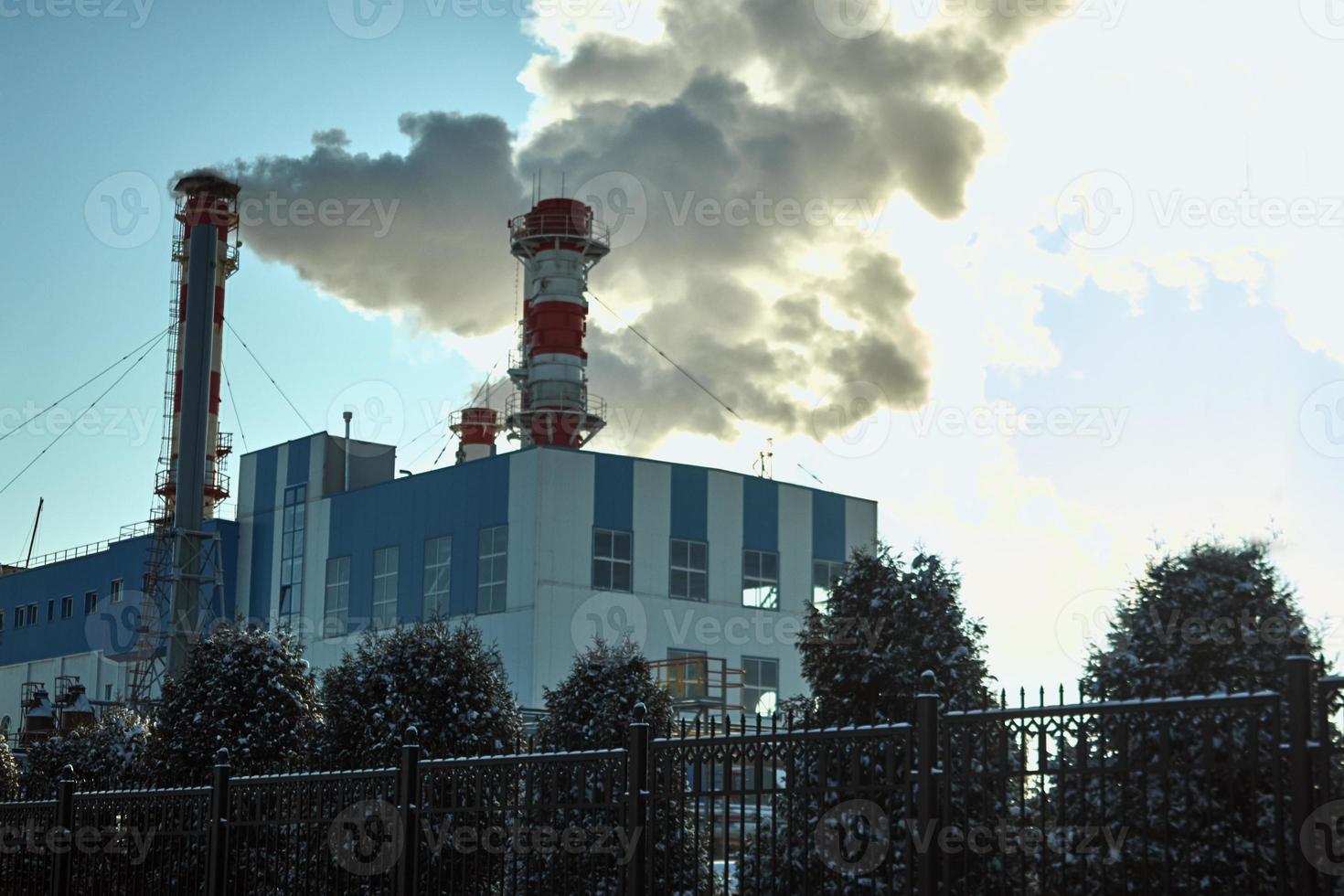 Air pollution with smoke from a plant chimney in winter sky photo