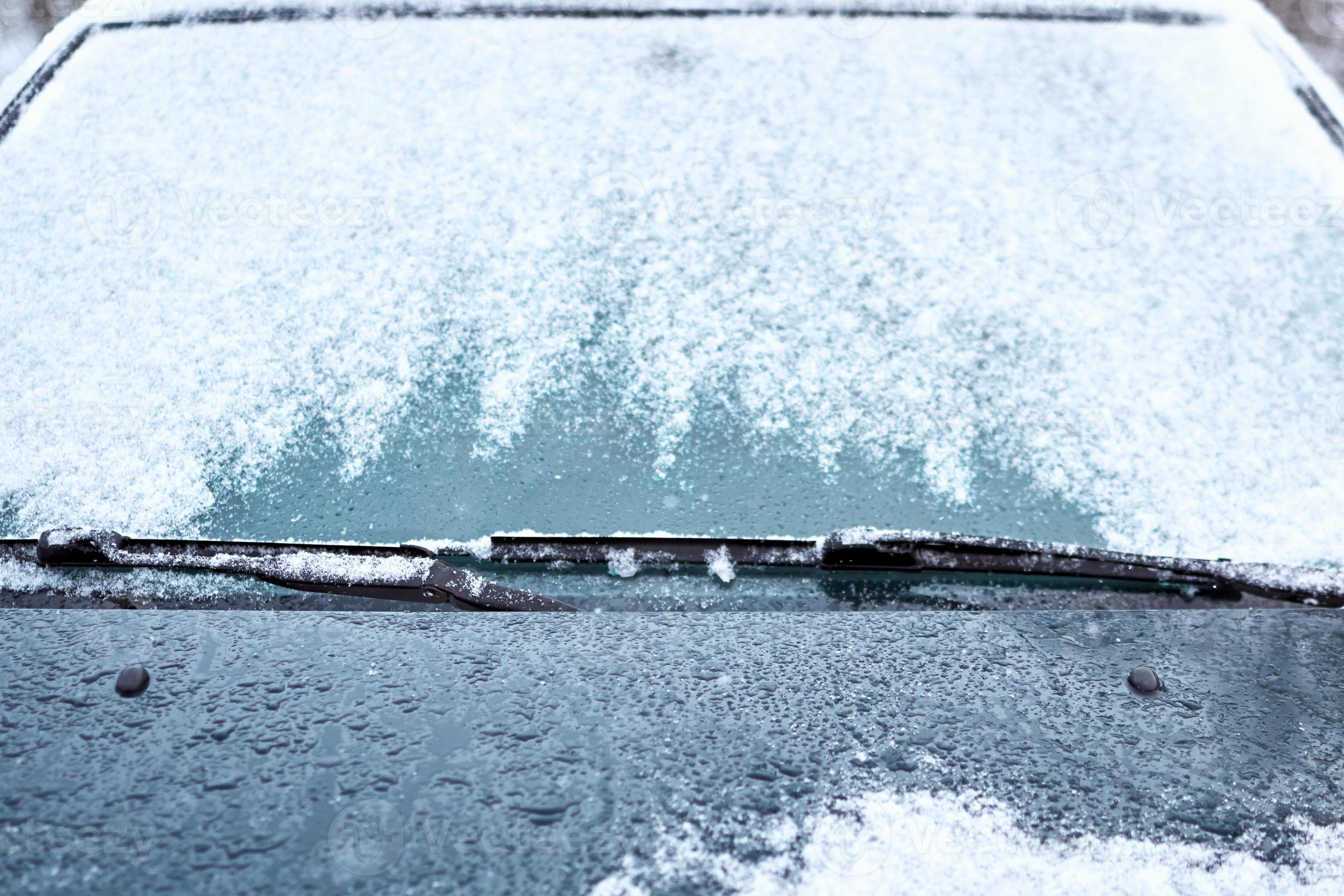 Close up of car windshield and wipers covered with ice and snow on