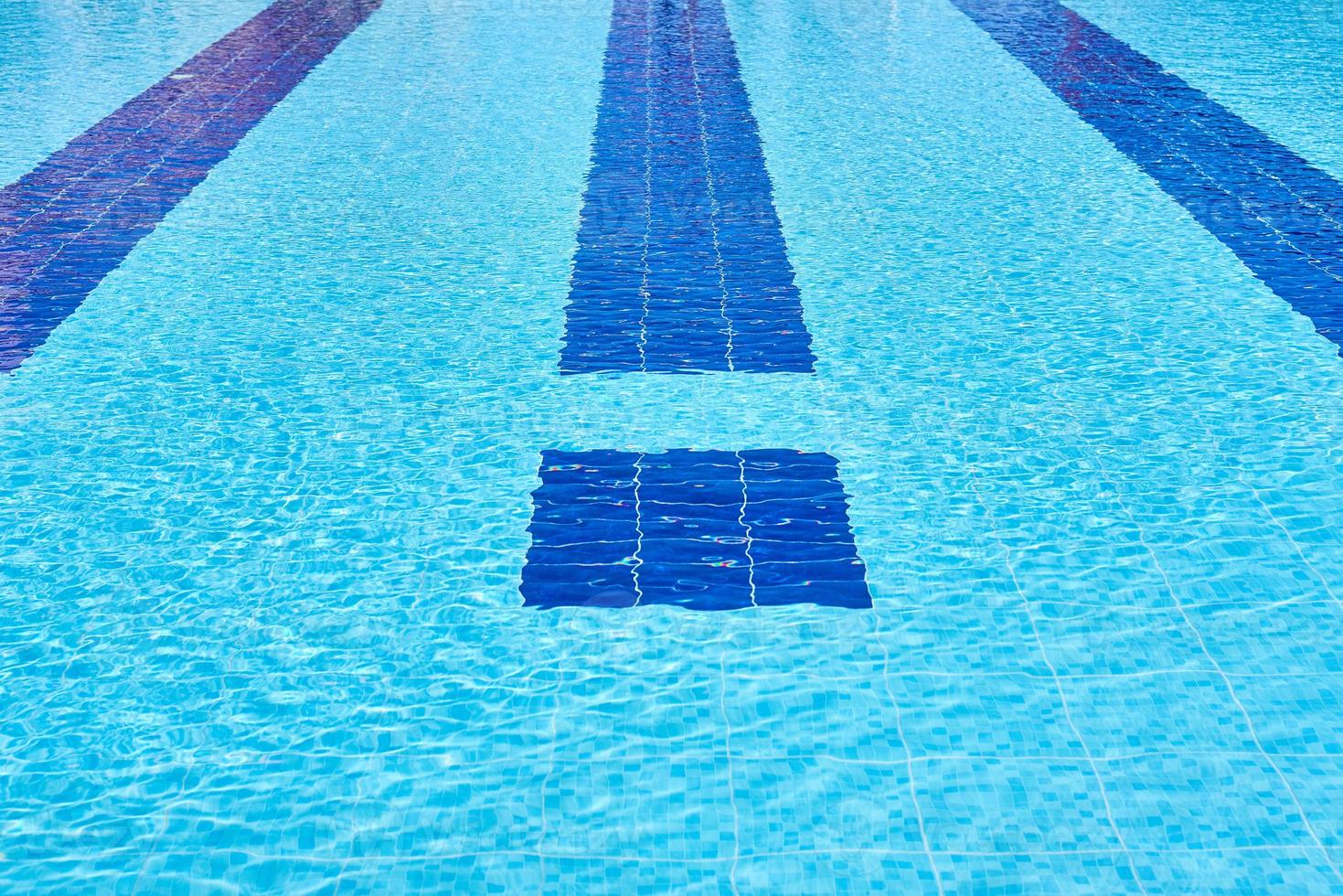 Background of water in blue swimming pool, water surface with a sun reflection photo