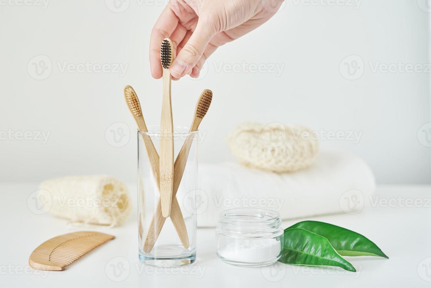 Woman hand take wooden bamboo toothbrush in a bathroom interior photo