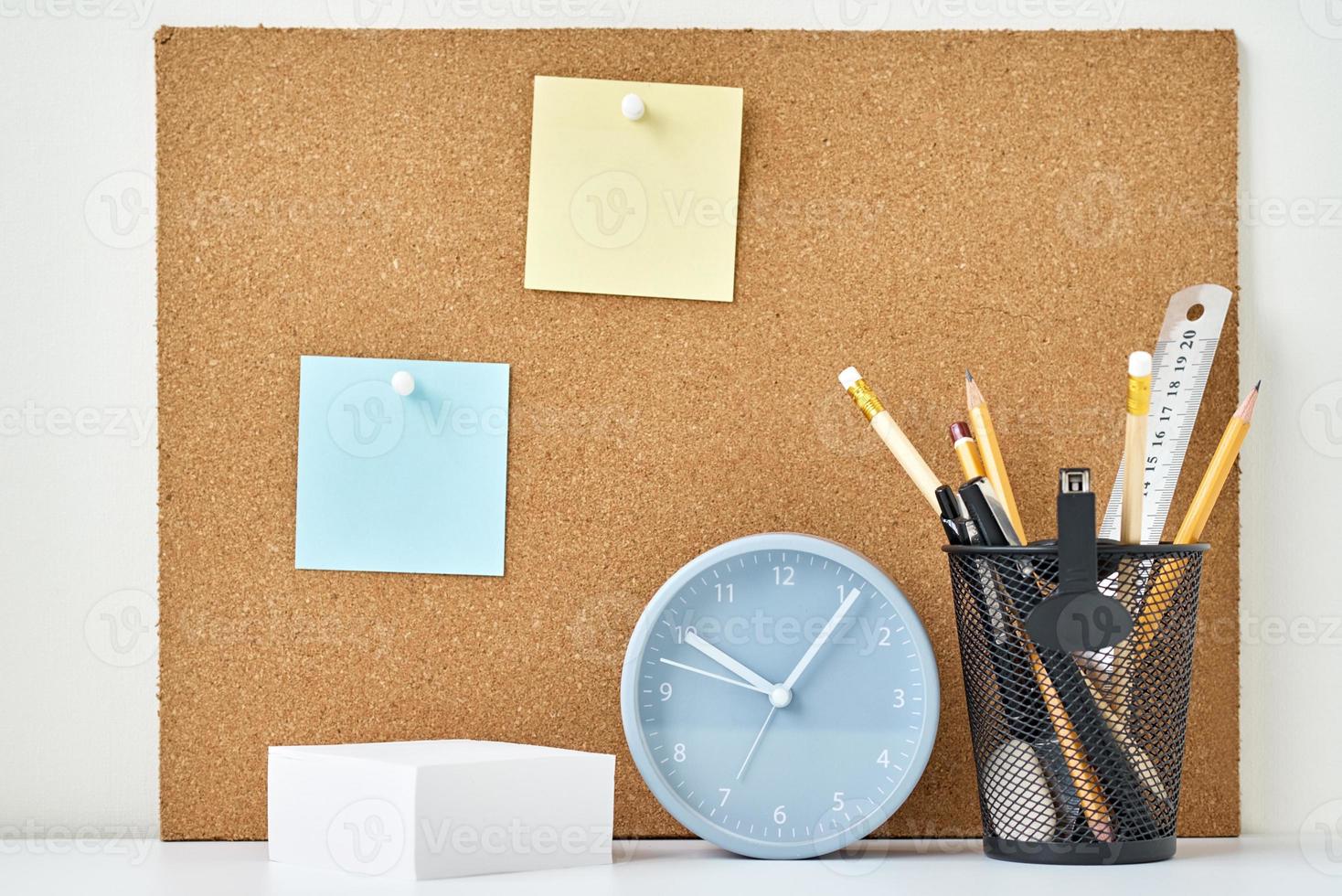 Sticky notes on a cork board, alarm clock and stationary photo