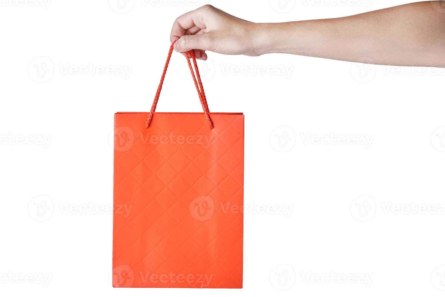 Woman hand hold red empty blank craft paper shopping bag isolated on white background. Packaging template mockup photo