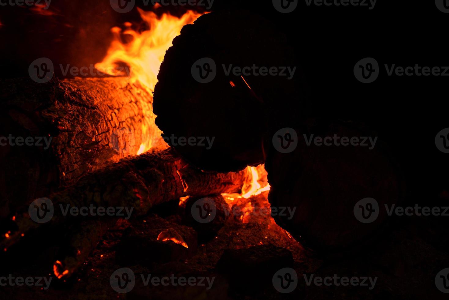 bonfire with a sparks at night. Heat from burning logs and coals in the dark photo