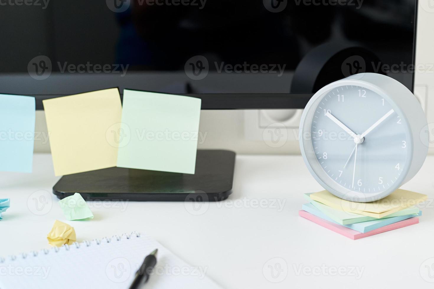 Workplace with a clock, office supplies and sticky notes photo