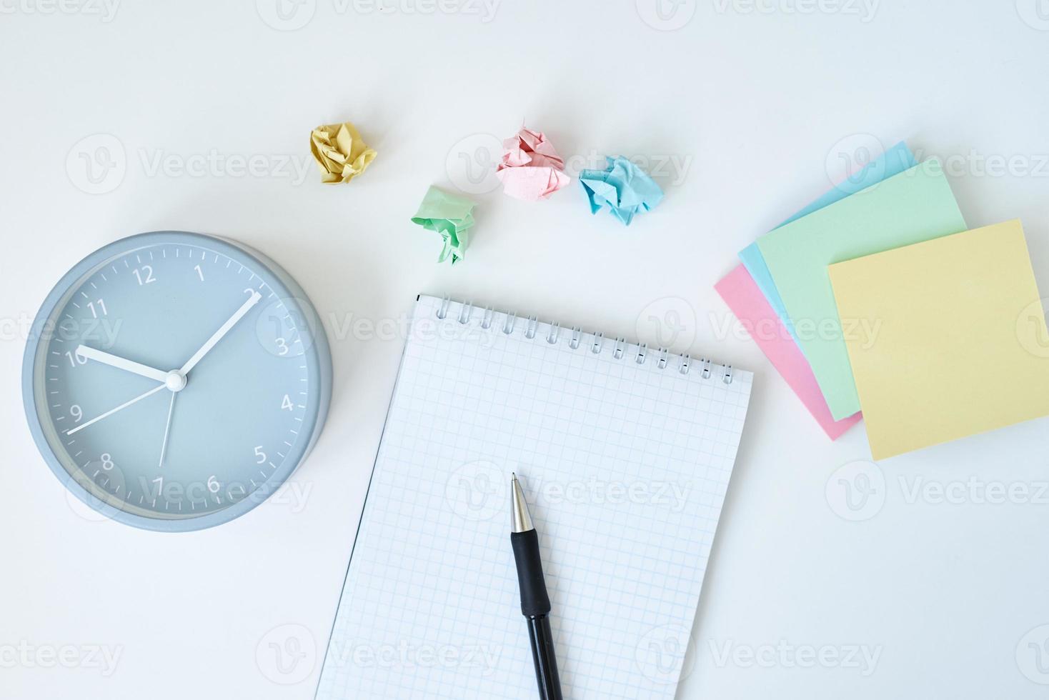 Gray round alarm clock colorful sticky notes and notebook photo