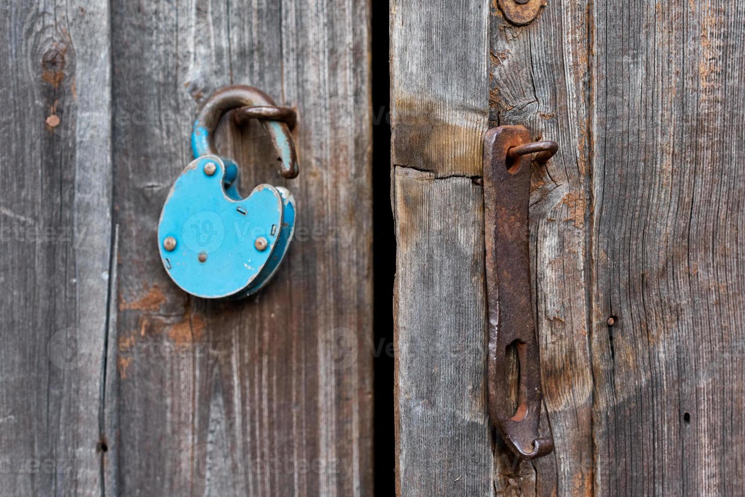 Blue old rusty unlocked padlock on wooden door photo