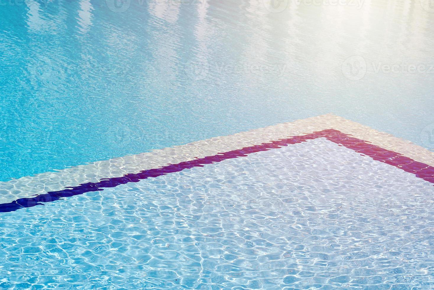 Background of water in blue swimming pool, water surface with a sun reflection photo