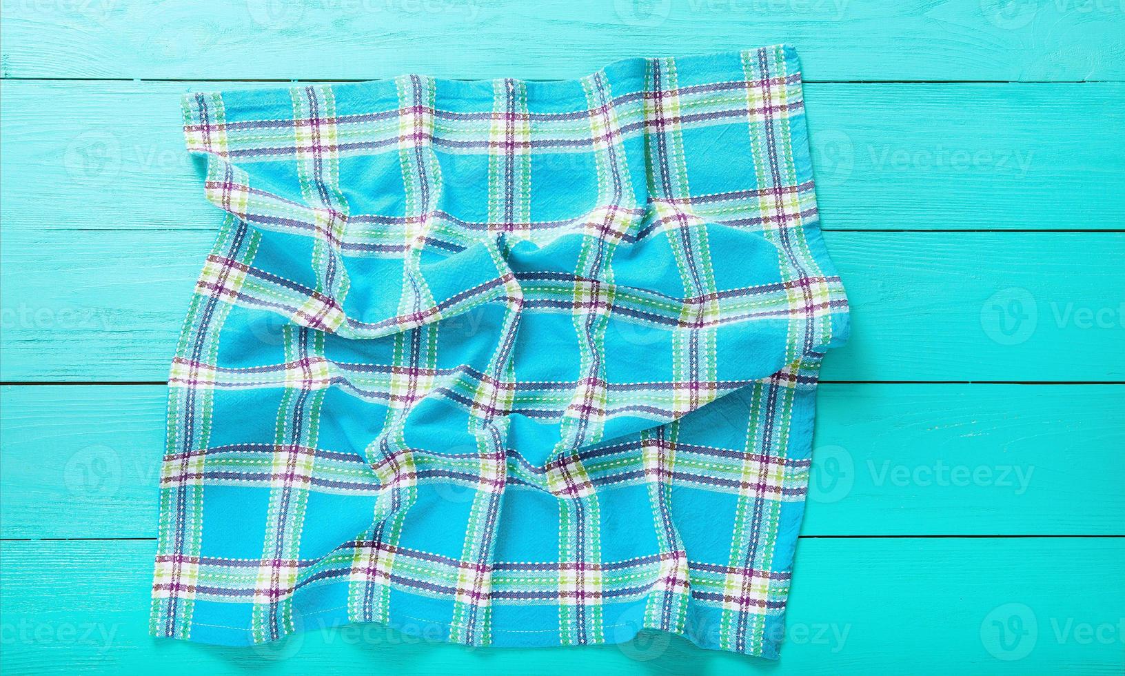 Plaid cloth background with copy space on blue wooden table. Top view and place for text photo