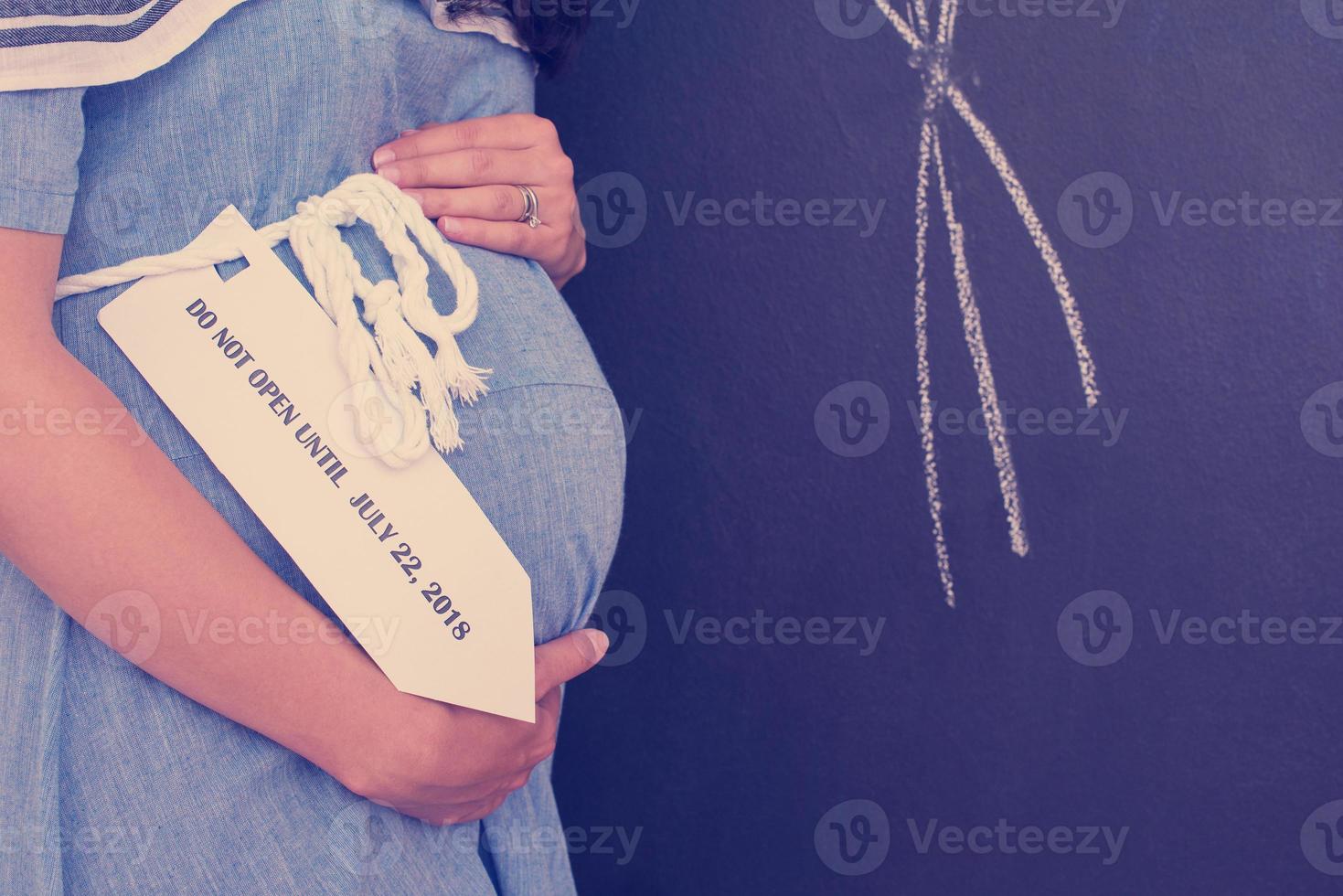 Portrait of pregnant woman in front of black chalkboard photo