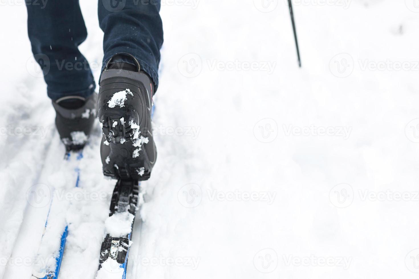 Feet of a skier in ski boots on cross-country skis. Walking in the snow, winter sports, healthy lifestyle. Close-up, copyspace photo