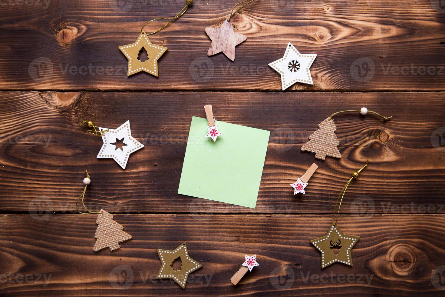 Christmas flat lay of wooden stars, fir trees and clothespins on a dark background with a square sheet for notes in the center. New year's frame, space for text. Xmas toys, to do list, a postcard photo