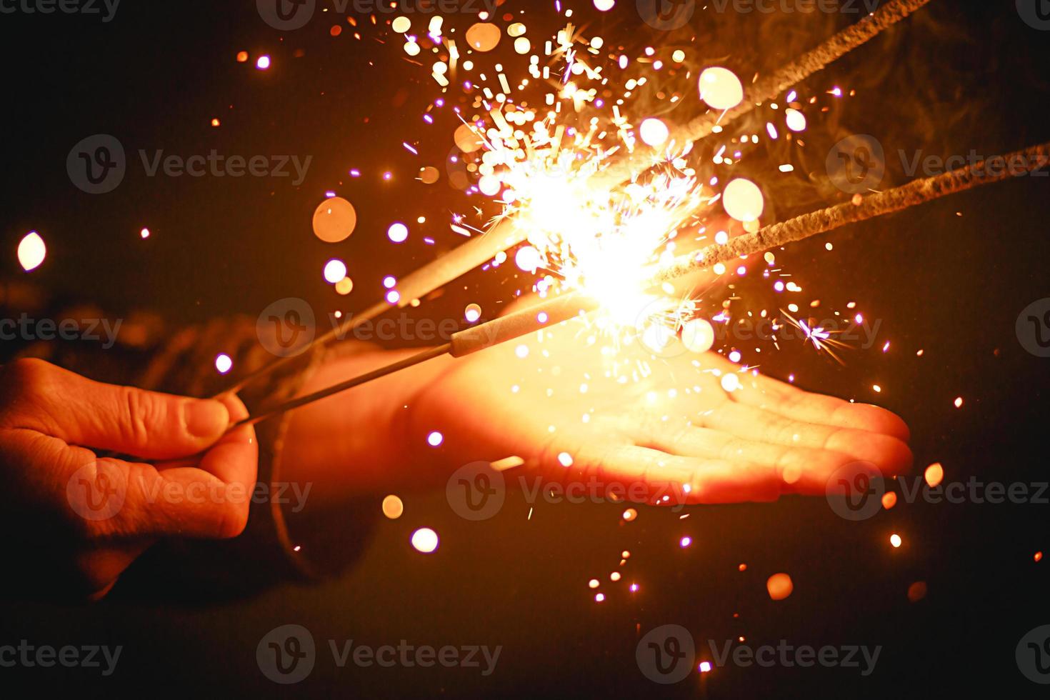 Sparks and light from sparklers in the dark on the palm of a person. Christmas magic, new year's eve, festive background. Space for text photo